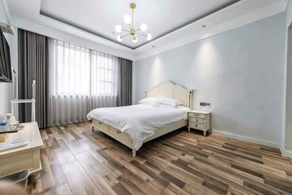 A bedroom with a bed, bedside tables, a desk, and a window with curtains.
