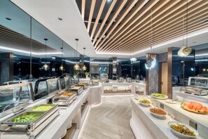 A buffet area with multiple food stations, a modern ceiling design, and a spacious layout.