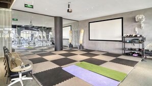 Um hall amplo com piso xadrez, uma tela grande e um espaço de estar com uma poltrona estampada.