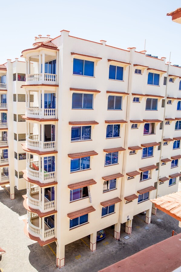 A multi-story hotel with balconies, large windows, and a tiled roof.