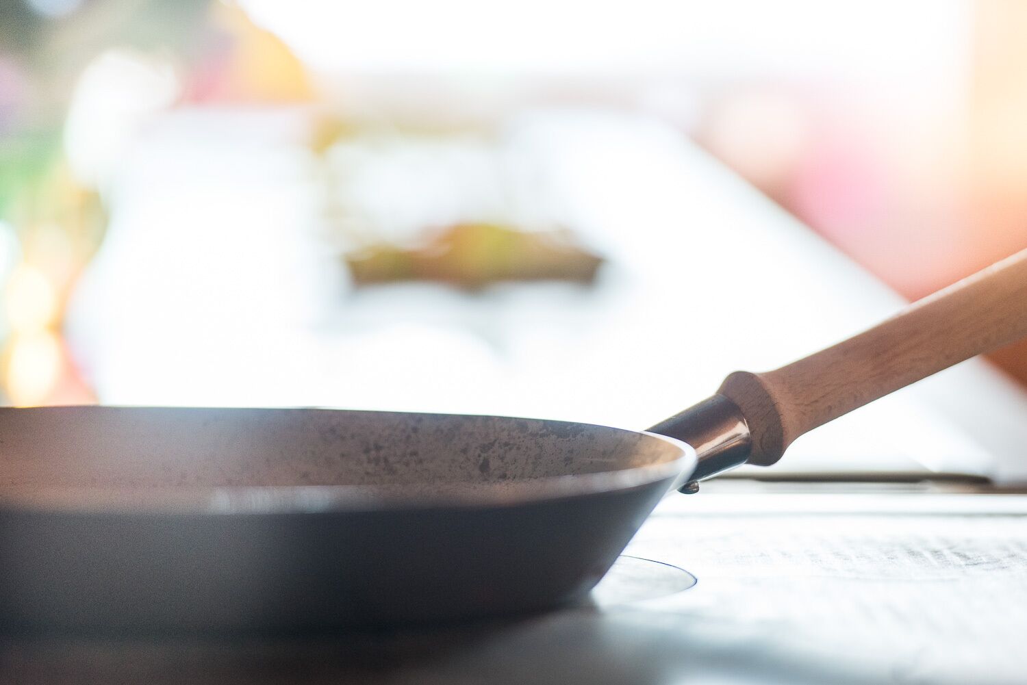 A close-up of a cooking pan with a wooden handle on a kitchen counter.
