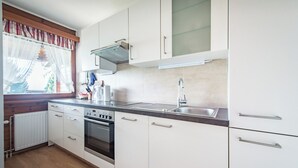 Egy modern konyha fehér szekrényekkel, rozsdamentes acél mosogatóval és egy Bosch sütővel.