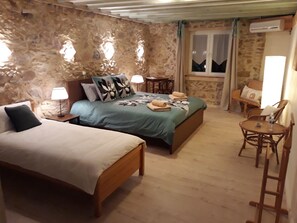 Un dormitorio con una cama, una cama individual, una silla, una mesa y un ventanal.