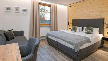 Ein Schlafzimmer mit einem Bett, einem Schlafsofa, einem Tisch und einem Fenster mit Vorhängen.