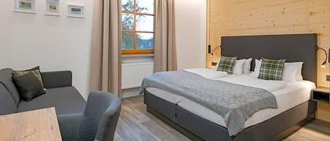 Ett sovrum med en säng, en soffa, ett bord och ett fönster med gardiner.