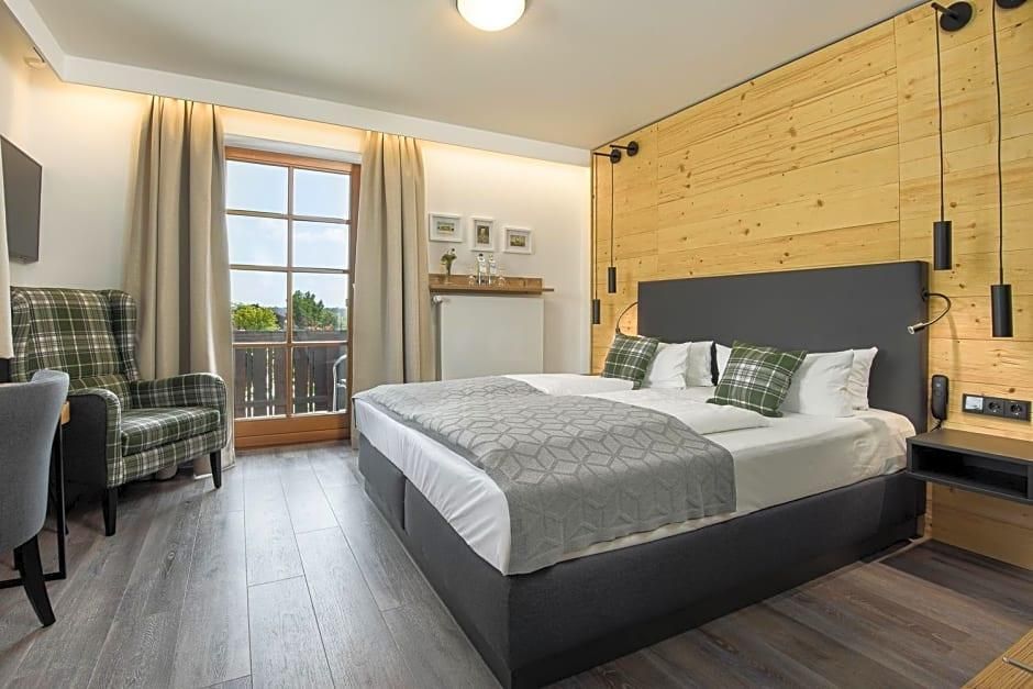 Ein Schlafzimmer mit einem Bett, einem Sessel, einem Fenster mit Vorhängen und einer Holzwand.