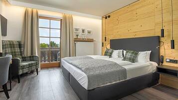 Ein Schlafzimmer mit einem Bett, einem Sessel, einem Fenster mit Vorhängen und einer Holzwand.