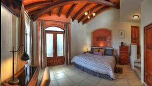 Un dormitorio con una cama grande, un armario de madera y un escritorio con lámpara.