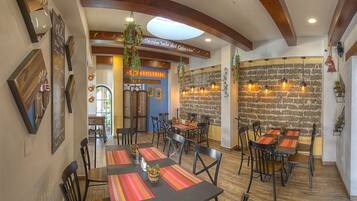 A restaurant with multiple tables and chairs, a brick wall, and hanging plants.