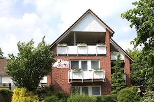 A two-story hotel with a red brick facade, balconies with white railings, and a sign indicating it is a hotel.
