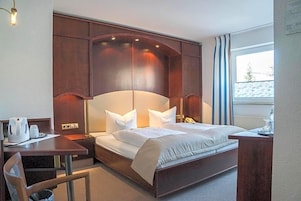A hotel room with a large bed, a desk, and a chair.