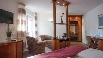 Une chambre d’hôtel équipée d’un lit, d’un bureau, d’une chaise, d’une télévision et d’une fenêtre avec des rideaux.