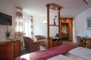 A hotel room with a bed, a desk, a chair, a television, and a window with curtains.