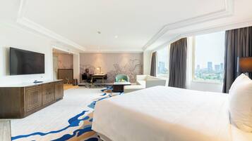 Habitación de hotel con una cama grande, un escritorio, una silla, un televisor y vistas a la ciudad.