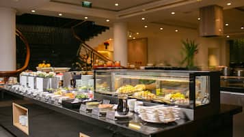 A buffet counter with various food items, a glass display case, and a staircase in the background.