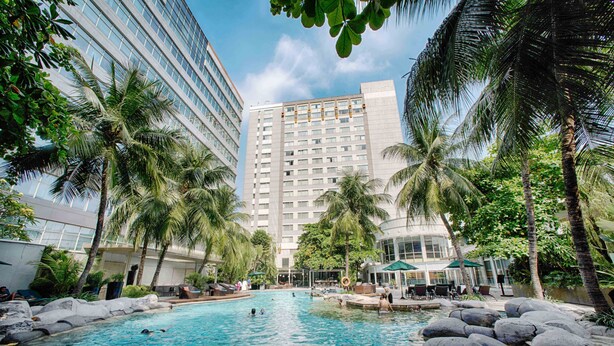 A hotel pool surrounded by palm trees and modern buildings. - Wyndham Casablanca Jakarta (Jakarta)