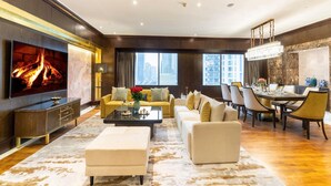 A spacious living room with a flat-screen TV, sofas, a coffee table, and a dining area with chairs and a table. - Wyndham Casablanca Jakarta (Jakarta)