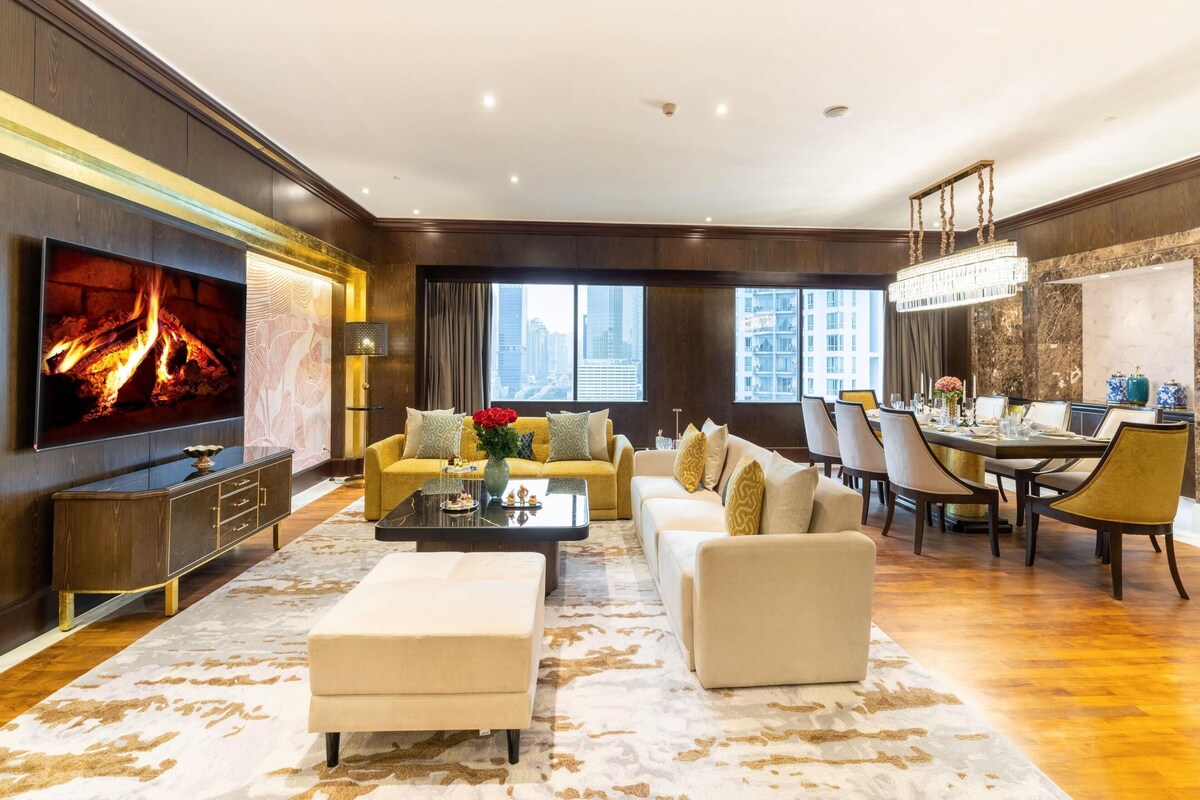 A spacious living room with a flat-screen TV, sofas, a coffee table, and a dining area with chairs and a table.