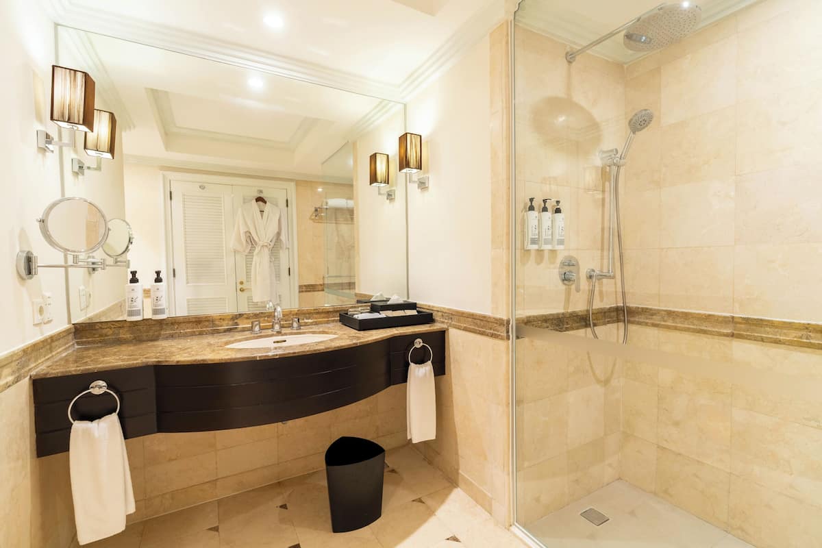 A modern bathroom with a large mirror, a shower, and a vanity with a sink and towel rack.