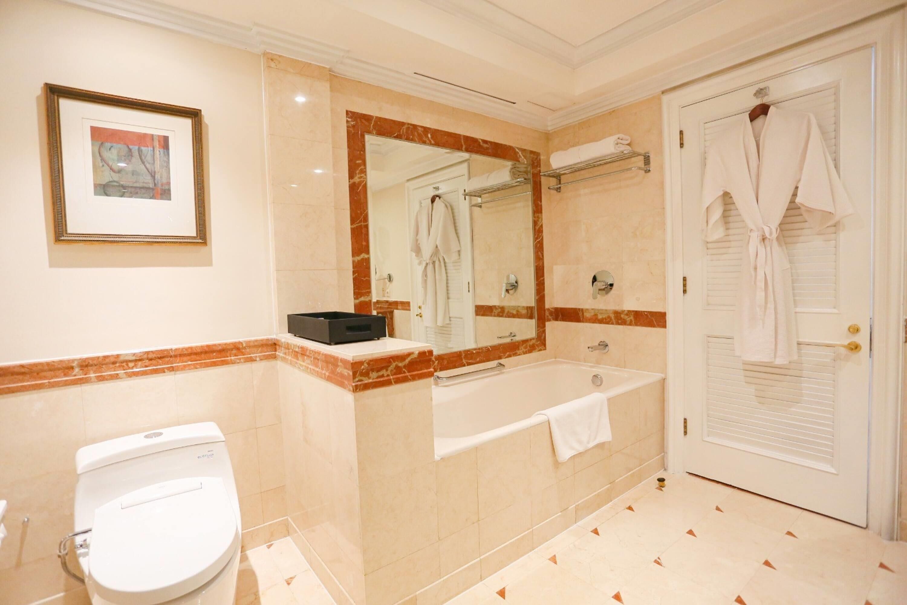 A bathroom with a toilet, a bathtub, a sink, a mirror, and a door.