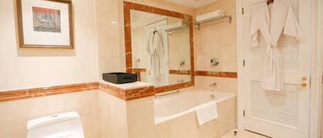 Un baño con inodoro, bañera, lavamanos, espejo y puerta.