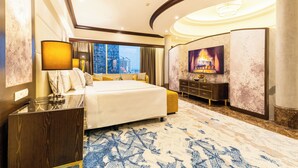 A spacious hotel room with a large bed, a nightstand, a desk, a chair, a television, and a city view. - Wyndham Casablanca Jakarta (Jakarta)