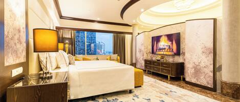 A spacious hotel room with a large bed, a nightstand, a desk, a chair, a television, and a city view.