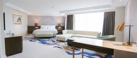 A hotel room with a bed, a sofa, a desk, and a large window.