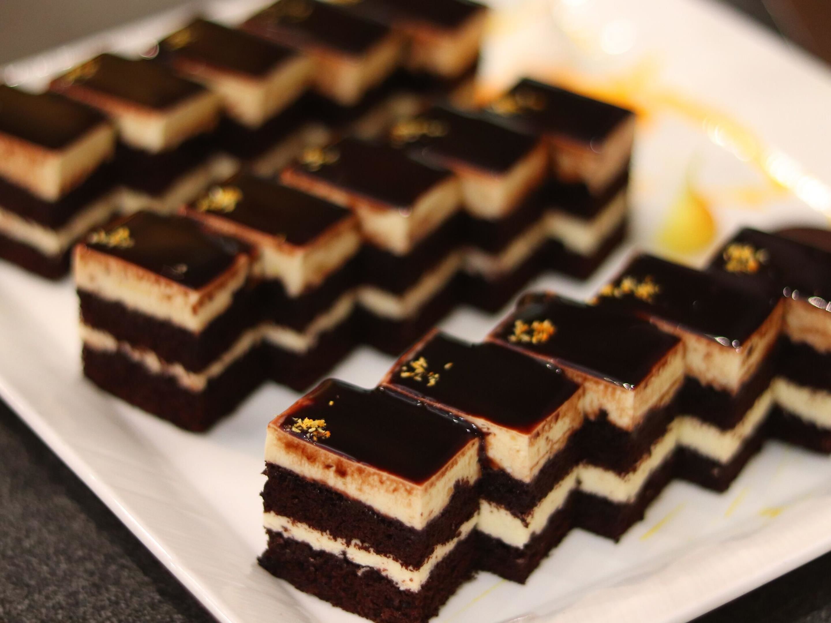 A white plate with several square pieces of layered dessert.