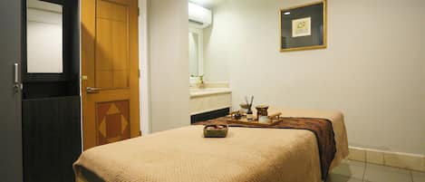 Une chambre d’hôtel avec un lit, une porte en bois, une petite table avec un plateau, et un tableau encadré au mur.