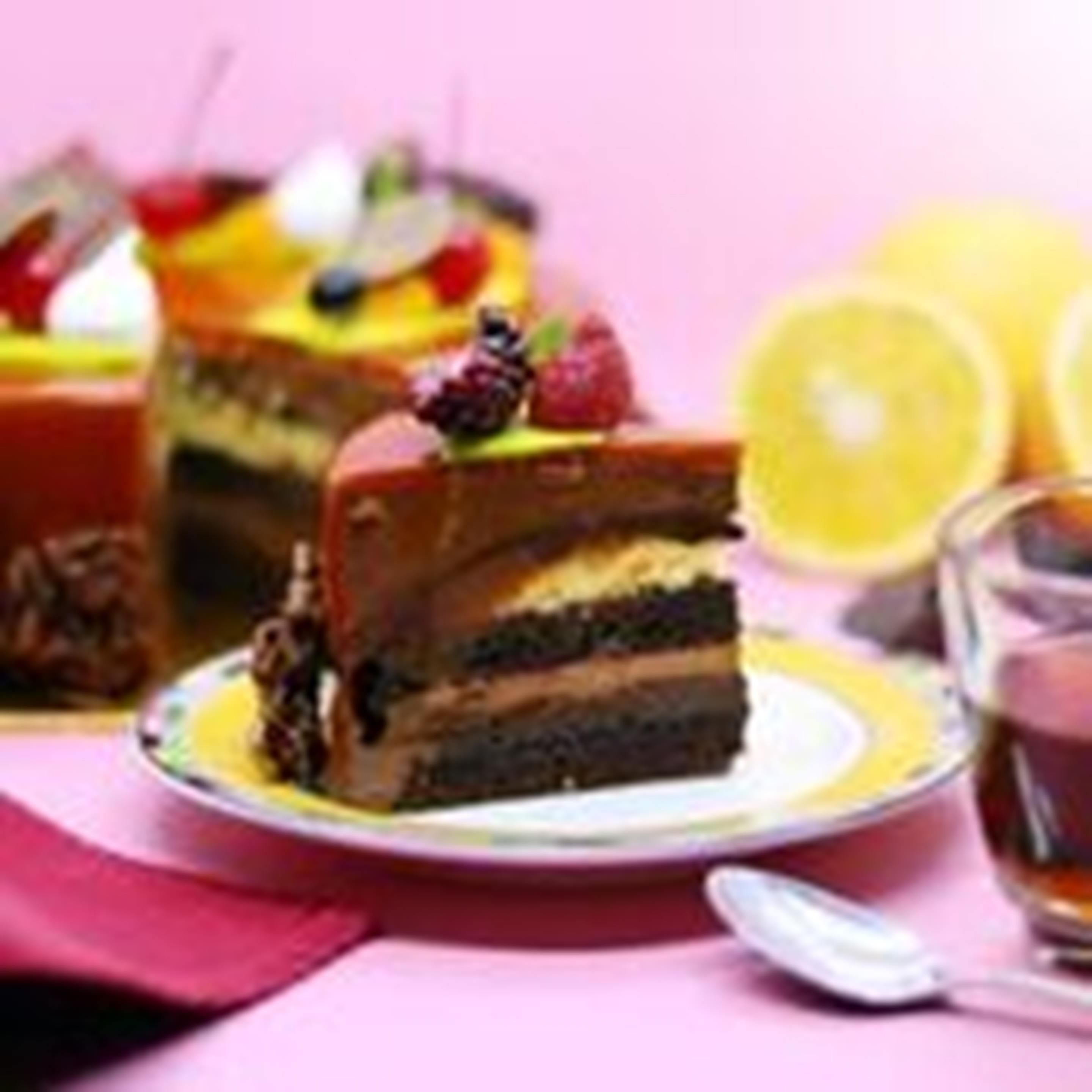 Una porción de pastel en capas con fruta encima, servida en un plato junto a una cuchara.