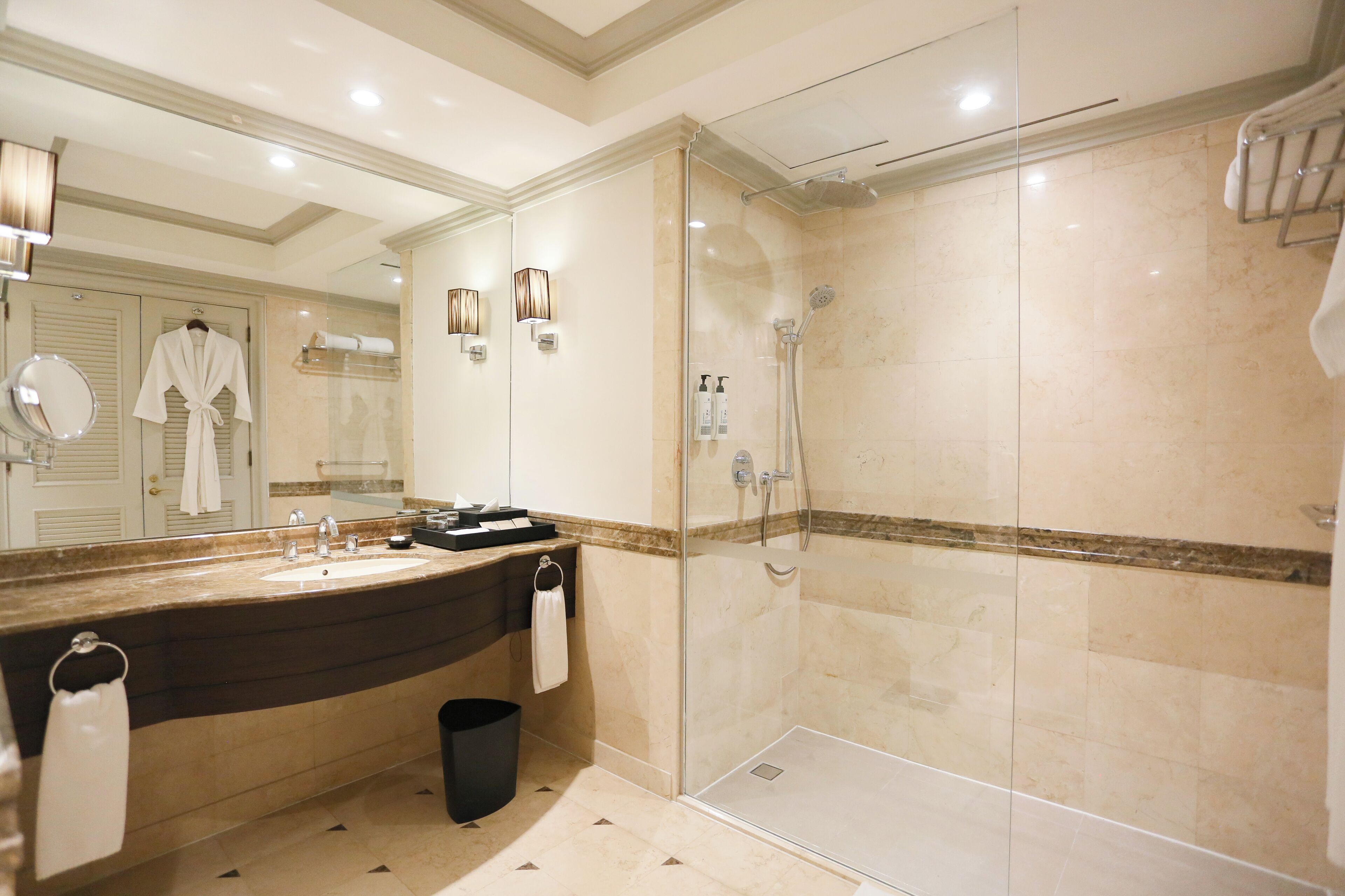 Een moderne badkamer met een grote spiegel, een wastafel, een douche en een douchecabine met glazen wanden.