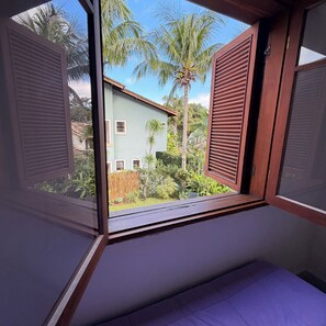 A room with a window overlooking a garden and a house.