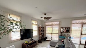 A living room with a sofa, TV, bookshelf, and a ceiling fan. - New Year's Eve 2026 - house + housekeeping services. Convenience and comfort (São Sebastião)