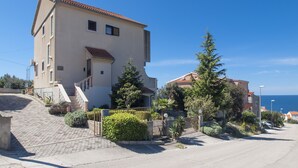 A two-story building with a tiled roof, a staircase leading to the entrance, and a paved driveway. - APARTMAN MIKELIN(2+1) AND 2 ROOMS(EACH FOR 2 PEOPLE) (Primošten)