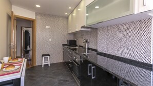 A modern kitchen with black countertops, stainless steel appliances, and patterned backsplash. - Casa Campolide - Lisbon (Lisboa)