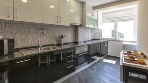 A modern kitchen with a black countertop, stainless steel appliances, and a tiled backsplash. - Casa Campolide - Lisbon (Lisboa)