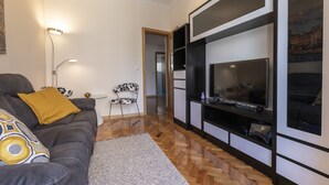 A modern living room with a sofa, a TV, and a bookshelf. - Casa Campolide - Lisbon (Lisboa)
