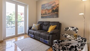 A living room with a sofa, a glass coffee table, a painting, and a floor lamp. - Casa Campolide - Lisbon (Lisboa)