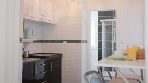Una cocina moderna con gabinetes blancos, encimera negra y un pequeño comedor con mesa y sillas.