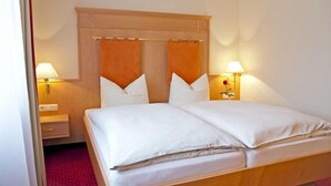 A double bed with a wooden headboard, two bedside lamps, and a red carpet. - Rosenhof (Kerpen)