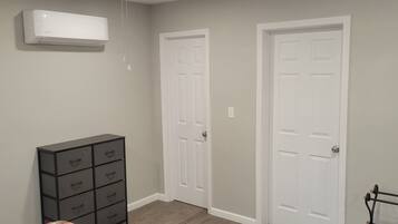 A room with a white air conditioning unit, a black filing cabinet, and two white doors.