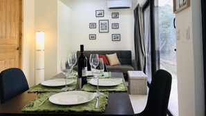 A dining area with a table set for two, a bottle of wine, and a sofa in the background. - Tamarindo 2 BR, 2 BA  (tamarindo)