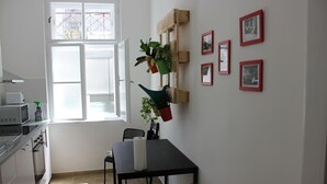 Eine Küche mit Esstisch, Stühlen und einem Fenster mit geöffneten Rollos.