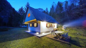 Una piccola casa con tetto spiovente, un patio e un tavolo con sedie all'esterno.