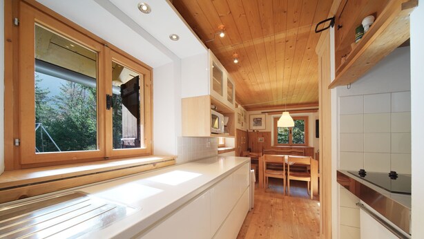 Una cucina moderna con mobili in legno, un piano di lavoro bianco e una finestra che si affaccia sul verde.