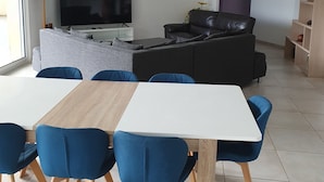 Un saló modern amb televisió, sofà i zona de dinar amb cadires.