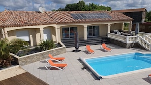 Zona de piscina amb solàrium enrajolat, una piscina i gandules taronges.