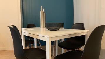 A modern dining area with a white table, black chairs, a metal vase, and a woven basket.