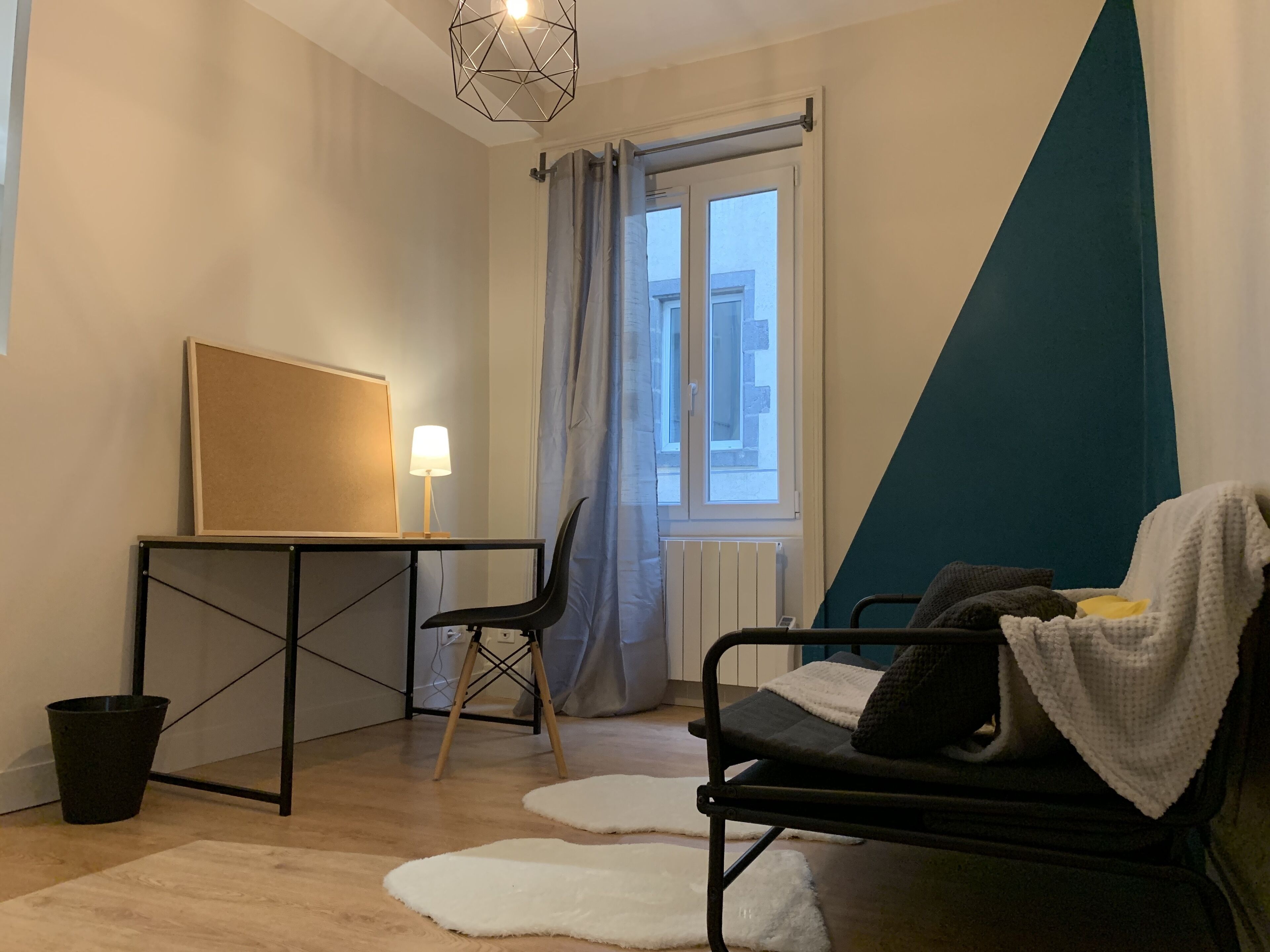 A modern room with a desk, chair, and a bed with a blanket.